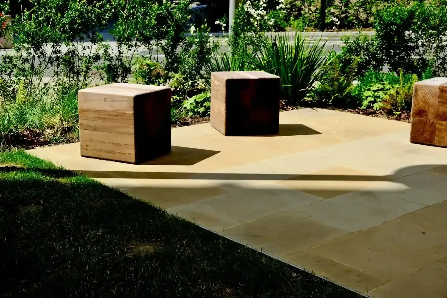 Strak gelegd natuurstenen terras met houten zitblokken en beplanting eromheen